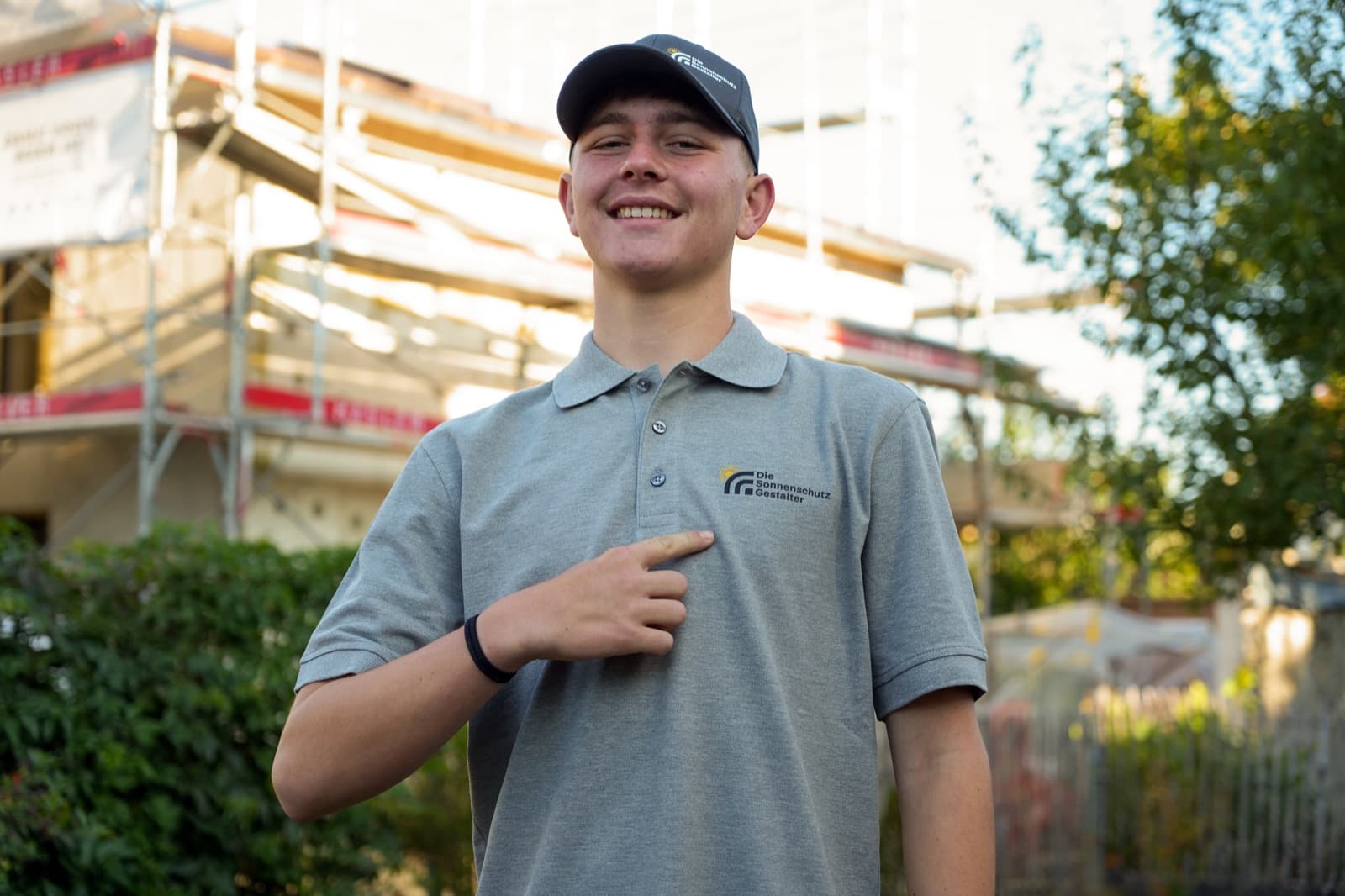 Lernender zeigt auf das Logo auf seinem Poloshirt